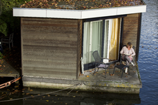 852181 Portret van Mieke, bewoner van een woonboot aan de Wittevrouwenkade te Utrecht, gezeten op het terras van haar ...